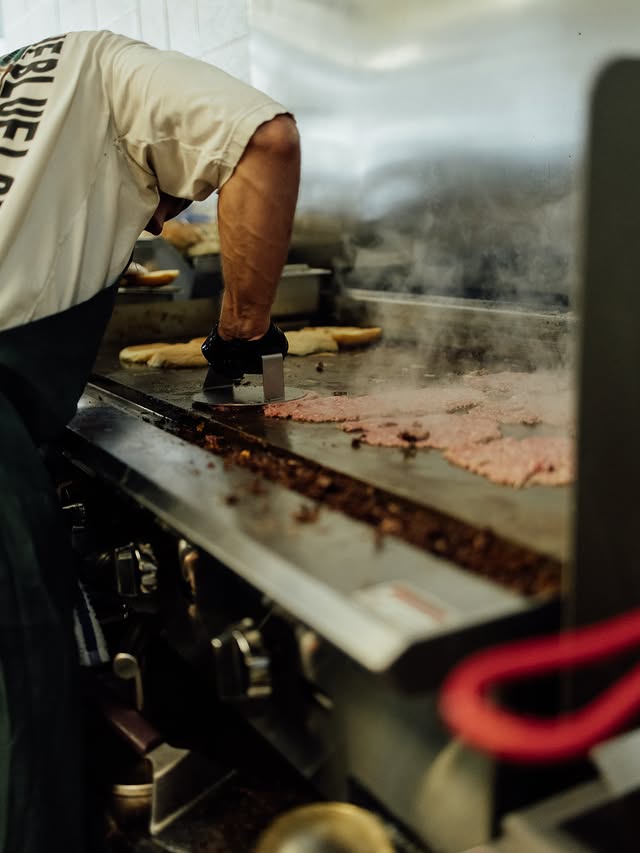 Smashing grass-fed beef patties on the flat-top griddle at Tallow House in Cleveland, TN
